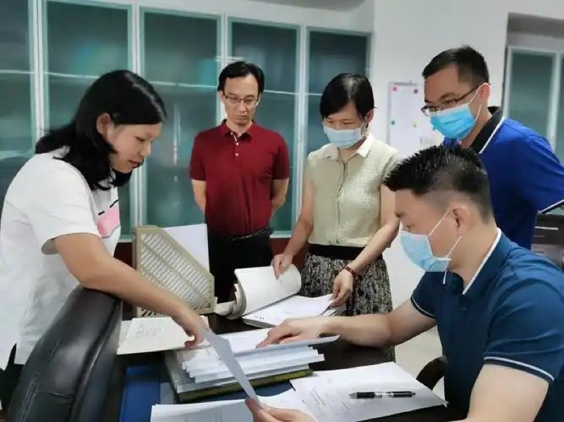 质量与生产团队一起核对成堆的体系文件与记录